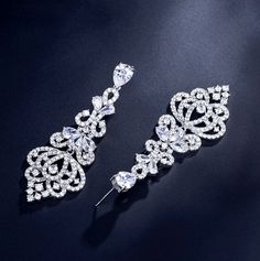 Elegance, sparkle and fluid motion define this exquisite pair of bridal earrings. All it takes is a simple glance at this unique design to see its extremely classy look that will add glamour and sophistication to any bridal gown or formal ensemble. Length: 2" (approx. 5cm); Width: 1" (approx. 2.3cm); Weight: 12g Choose between Rose Gold, Silver and Yellow Gold finishes. To make your choice select from the dropdown menu. Hypoallergenic - lead, nickel and cadmium free. Cubic Zirconia Bridal Earrings, Date Night Dress, Beautiful Handbags, Date Night Dresses, Rose Gold Earrings, How To Look Classy, Bridal Earrings, Chandelier Earrings, Bracelet Set