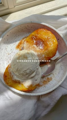 a bowl filled with ice cream and two pieces of fruit on top of a white cloth