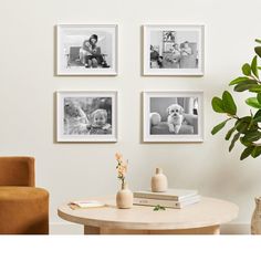 four black and white photos hang on the wall above a table with a vase, potted plant and books