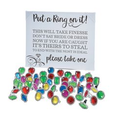 a bunch of colorful brooches sitting next to a sign that says put a ring on it