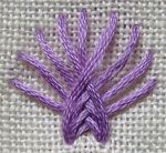 a close up of a purple thread on a white cloth