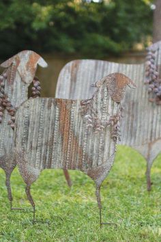 two metal sheep sculptures sitting in the grass