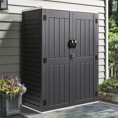 a large gray storage shed sitting next to a flower pot on the side of a house