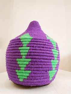 a purple and green basket sitting on top of a white table next to a wall