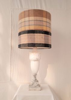 a lamp that is sitting on top of a white table with a checkered shade