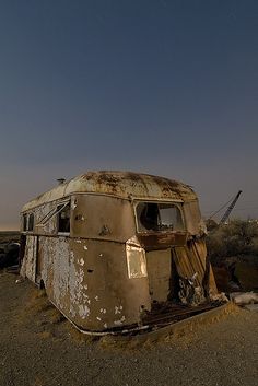 an old rusted out trailer sitting in the middle of nowhere