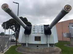 two large metal tanks sitting on top of a lush green field next to a building