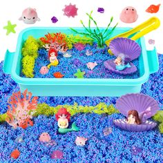 an aquarium filled with blue sand and little mermaid figurines on top of it