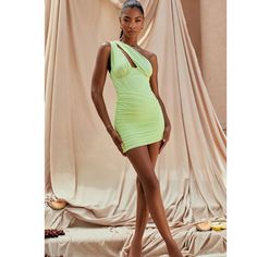 a woman in a short neon green dress posing for the camera with her legs crossed