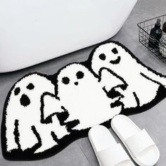 two ghost rugs and slippers on the floor next to a bathtub with white slippers