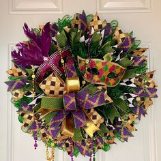 a purple and green wreath hanging on the front door with gold bowknots