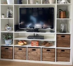 an entertainment center with white shelving and lots of storage bins on each side