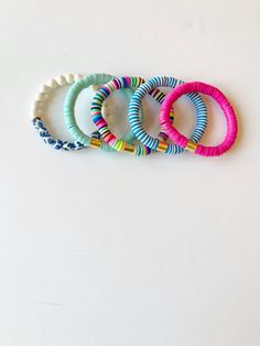 four different colored bracelets sitting on top of a white table next to each other