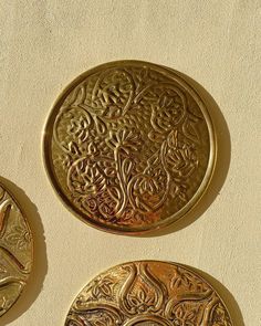 three gold medallions sitting on top of a white wall