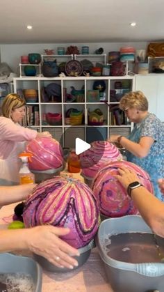 three women in a kitchen preparing food with bowls on the counter and one woman is washing her hands