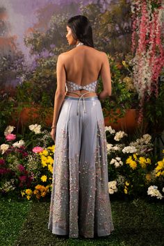 Element of fun and ethereal crafted in one ensemble. Sofia co-ord set consists of a halter neck top paired up with wide-legged pants accentuated with tassel drops. The ice-blue hue of the ensemble makes one look surreal and elegant while at the same time, the silhouette defines your bubbliness. Halter neck blouse embroidered with daisy motifs highlighted with sequins and flowers. Wide-legged pants with attached crisscross studded straps at the waistline crafted out of blingy sequined fabric high Indian Outfits Pants, Festive Party Palazzo Set With Tassels, Blue Palazzo Set For Spring Party, Chic Sets For Spring Reception, Chic Spring Reception Sets, Elegant Sequined Palazzo Set For Summer, Summer Embellished Pant Set For Party, Floor-length Spring Party Palazzo Set, Floor-length Palazzo Set For Spring Parties