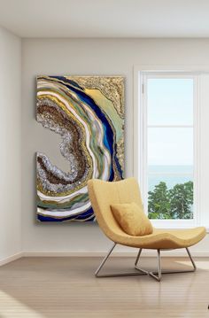 an abstract painting hangs on the wall next to a chair in front of a window