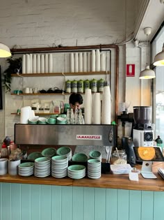 a counter with plates and cups on it in a restaurant or coffee shop, surrounded by hanging lights