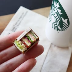 a tiny sandwich ring sitting on top of a napkin next to a starbucks coffee cup