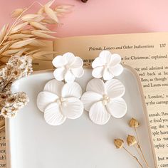 three white flowers sitting on top of an open book