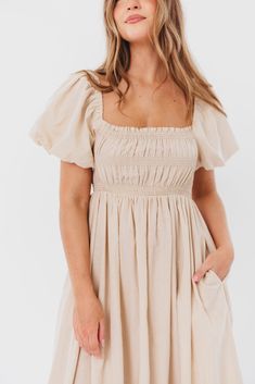 Be the life of the party in the Nan Maxi Dress! This beautiful gown comes in a gorgeous, multi-season neutral hue, and features a smocked bodice and puffed sleeves that can be worn on or off the shoulder - it's like getting two dresses in one! Style the Nan with slides for a casual, feminine outfit, or with neutral heels for the perfect event dress. FIT: Runs true to size. MATERIAL: GARMENT DETAILS: Neutral maxi dress with empire waist silhouette, smocked bodice, and puffed sleeves with elastica Puff Sleeve Midi Dress For Garden Party, Garden Party Puff Sleeve Dress With Smocked Back, Puff Sleeve Dress With Smocked Back For Garden Party, Garden Party Puff Sleeve Dress With Ruched Bodice, Garden Party Dress With Puff Sleeves And Ruched Bodice, Spring Puff Sleeve Dress For Gatherings, Feminine Smocked Dress With Gathered Sleeves And Square Neck, Feminine Smocked Dress With Square Neck And Gathered Sleeves, Flowy Smocked Bodice Puff Sleeve Dresses