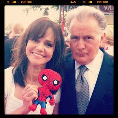 an older man and young woman posing for a photo with a spider - man toy