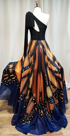 a dress on display in front of a white curtain with black and orange butterflies painted on it