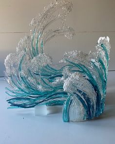 an artistic glass sculpture made to look like a peacock's tail is shown in front of a white background