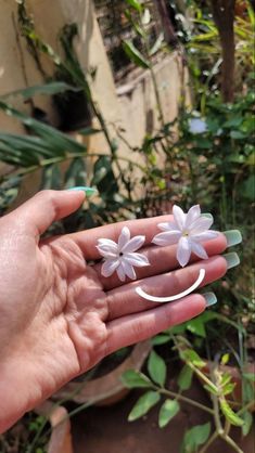 a person's hand holding three small white flowers in the middle of their palm