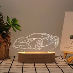 a car shaped lamp sitting on top of a table next to a potted plant