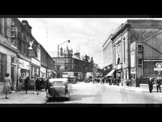 an old black and white photo of people walking down the street