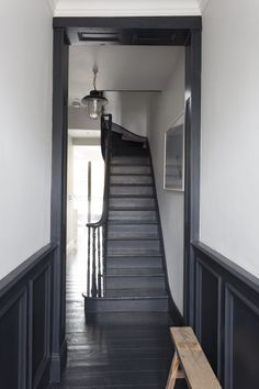 the stairs in this house are painted black and have white walls with dark wood trim