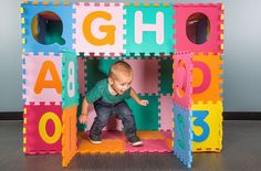 a small child is playing in a play house made out of foam blocks with numbers and letters