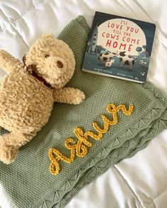 a teddy bear laying on top of a bed next to a book