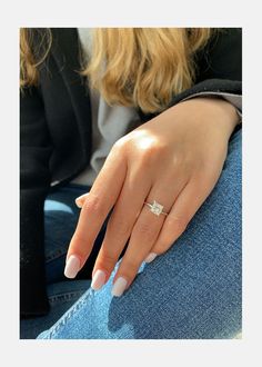 a woman's hand with a diamond ring on her left finger, sitting down