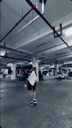 a man is walking in an empty parking garage with his back to the camera,