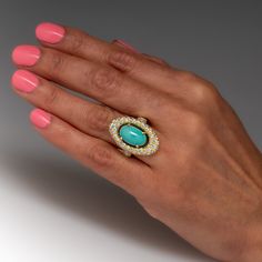 This captivating turquoise ring is centered with an oval turquoise cabochon, weighing an estimated 4.62 carats, in a four-prong setting. The center is surrounded by a halo, bead set with fifty-four (54) round brilliant cut diamonds. The shoulders are each bead set with ten (10) round brilliant cut diamonds. The ring measures 26.4mm at the top, rises 8.5mm above the finger, tapering to 2.4mm wide and 1.0mm thick at the base of the shank. The ring is currently a size 6. Luxury Oval Turquoise Ring With Polished Finish, Luxury Artisan Turquoise Oval Ring, Luxury Yellow Gold Turquoise Ring With Accent Stones, Luxury Yellow Gold Turquoise Ring, Oval Cabochon, Luxury Gold Turquoise Ring In Vintage Style, Luxury Oval Turquoise Ring, Luxury Turquoise Oval Cabochon Ring, Luxury Oval Turquoise Gemstone Ring, Elegant Oval Turquoise Ring With Center Stone