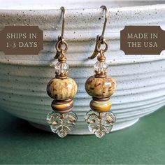 These Handmade Ceramic Earrings feature artisan craftsmanship with gold glass beads, creating an eclectic autumn aesthetic. Nature-inspired and finished with lever back closures, they make a unique gift for your spouse or mom. 𝗗𝗘𝗧𝗔𝗜𝗟𝗦 🍃 Earrings measure 1 and 5/8 inches from base of ear wires 🍃 Lever back ear wires made in the USA of lead/nickel free antiqued brass 🍃 Handcrafted ceramic beads with brown and gold glaze 🍃 Handcrafted European glass beads in earthy swirl 🍃 American brass and pewter throughout, antiqued and shiny 🍃 Czech glass leaf bead with gold veining 🍃 One of a kind design; don't miss out! 𝗛𝗢𝗪 𝗧𝗢 𝗢𝗥𝗗𝗘𝗥 1: Select item quantity 2: Select options, if applicable 3: Add to cart 4: Choose shipping method 𝗬𝗢𝗨 𝗔𝗟𝗦𝗢 𝗠𝗜𝗚𝗛𝗧 𝗟𝗜𝗞𝗘 Lever Back Earr Earthy Earrings, Beads Craft Jewelry, Ceramic Earring, Fall Earrings, Matching Jewelry, Jewelry Techniques, Earrings Inspiration, Fall Jewelry, Gold Glass