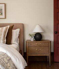 a bedroom with a bed, nightstand and red door