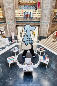 a large blue dog statue in the middle of a building with tables and chairs around it