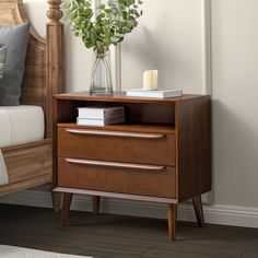 a bed with a wooden headboard and night stand next to a plant in a vase