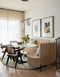 a living room filled with furniture next to a glass table and two pictures on the wall