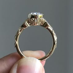 a person holding up a gold ring with two diamonds on the front and sides of it