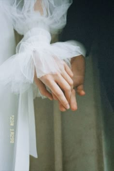 a close up of a person wearing a wedding dress and holding the hand of another person