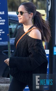 a woman in black sweater and leggings walking down the street with her hand on her hip