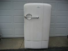 a white refrigerator sitting in front of a garage door