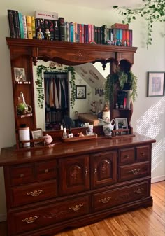 a large mirror sitting above a dresser in a room with books on top of it