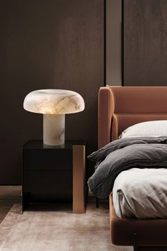 a bed sitting next to a night stand with a lamp on it's side