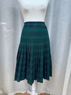 This is a beautiful skirt by Aljean Canada.  Plaid in green and navy colors.  Wool blend. Unlined, side zipper and button overlap closure. Marked size 14, fits size L us. Excellent vintage condition. Sizing is not marked but will fit US size S.  For a proper fit please see the measurements below. Measurements (flat): Waist: 25" Hips: 34" Shoulder to hem: 25,5" Green Pleated Knee-length Bottoms, Green Pleated Workwear Skirt With Lining, Green Pleated Skirt Lined For Workwear, Fitted Green Pleated Skirt With Lining, Retro Green Skirt For Fall, Green Knee-length Pleated Skirt For Workwear, Green Relaxed Fit Pleated Skirt For Work, Retro Green Pleated Skirt, Green Pleated Preppy Skirt