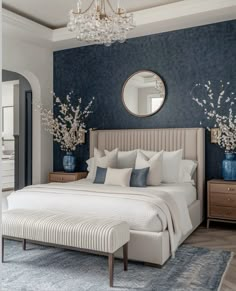 a bedroom with blue walls and white bedding, chandelier above the bed